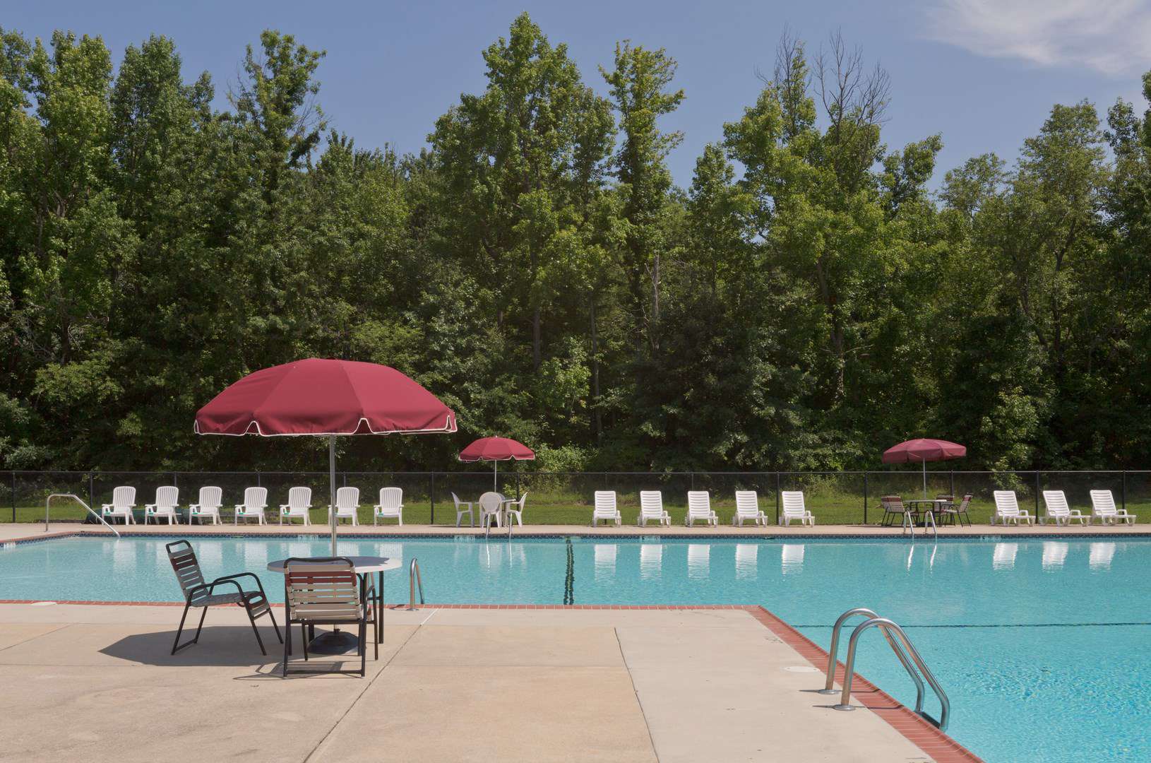 swimming pool with umbrellas, tables, and chairs at West Deptford apartment