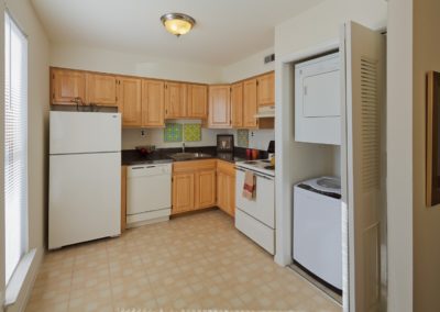 Kitchen in West Deptford, NJ Apartment with wooden cabinets, white appliances, and washer/dryer